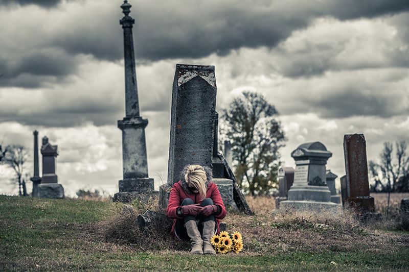 Woman crying in front of a tombstone