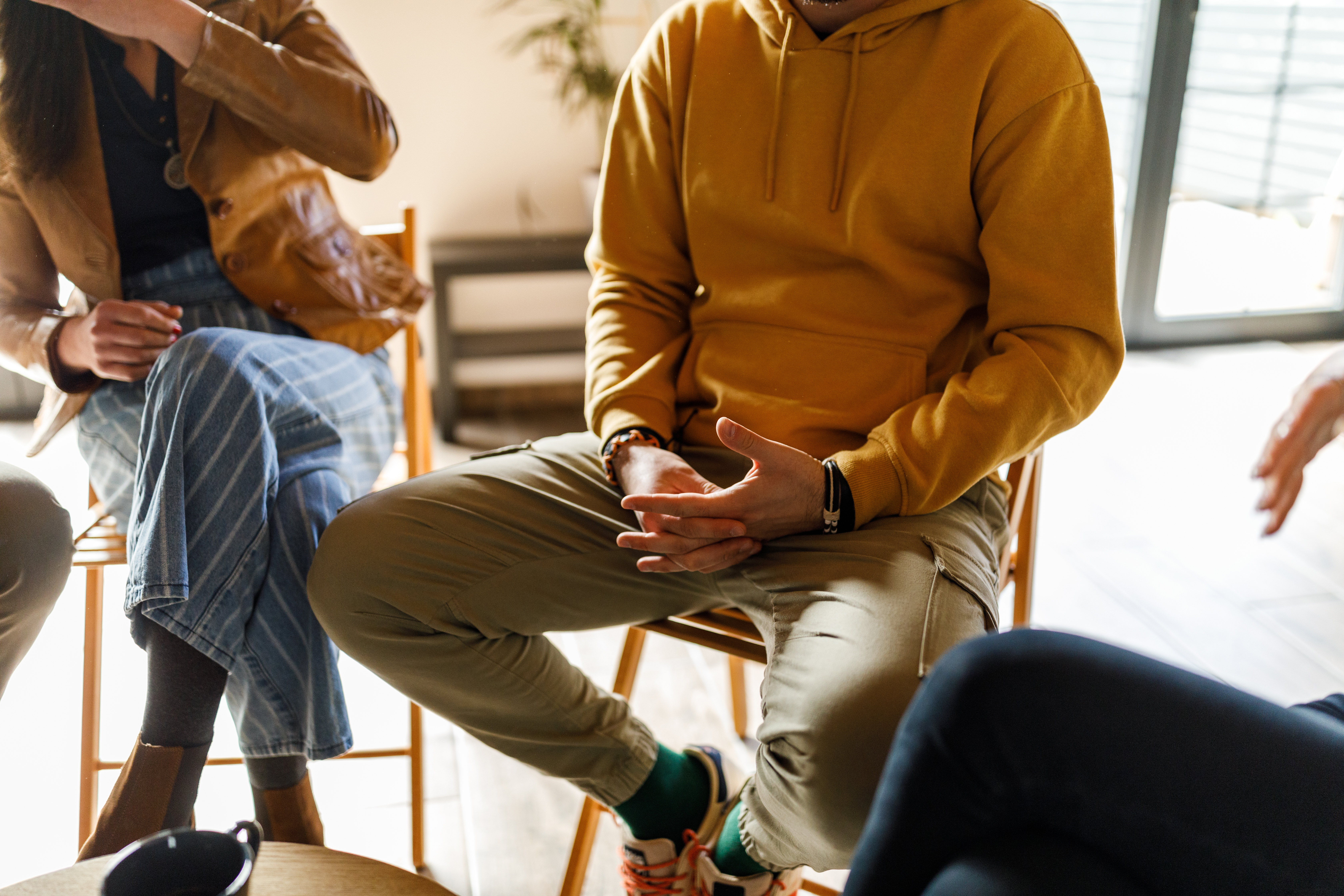 "Group therapy session with individuals sitting in a circle, sharing experiences and supporting one another in addiction recovery"